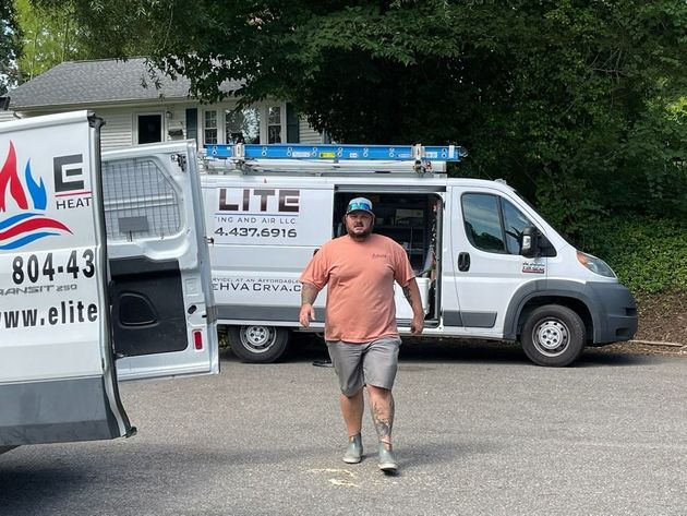 Man standing in front of LITE Service Vans parked on a driveway, with an open van door and trees nearby.
