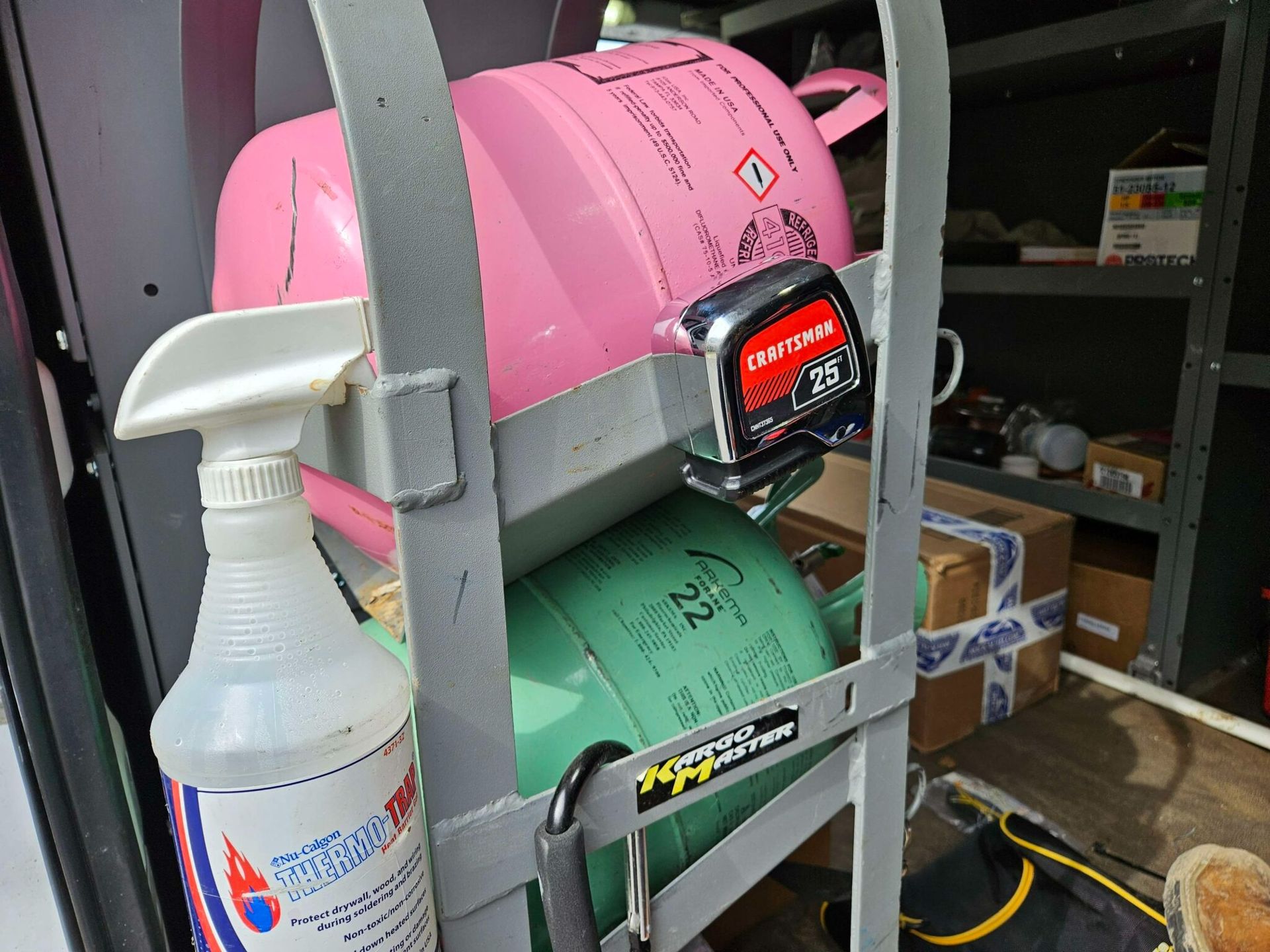 Spray bottle beside pink and green equipment in a cluttered storage room