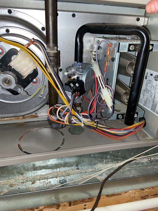 Open HVAC furnace panel with blower motor, control board, and colored wires visible.