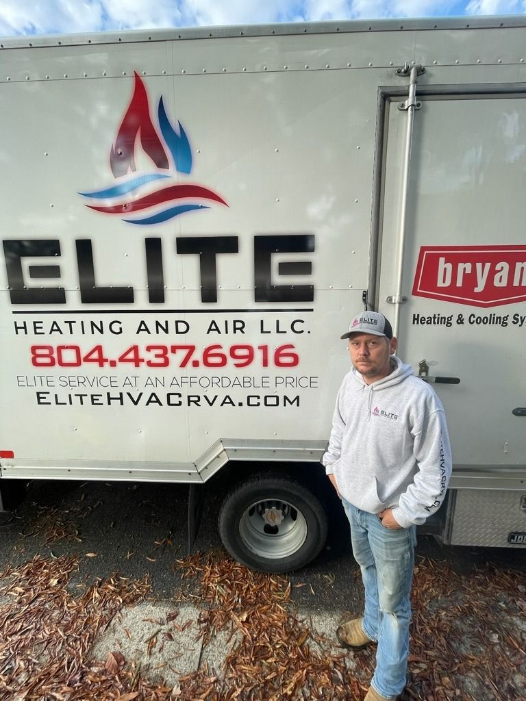 Man standing beside an Elite Heating and Air LLC service truck with company logo and phone number.