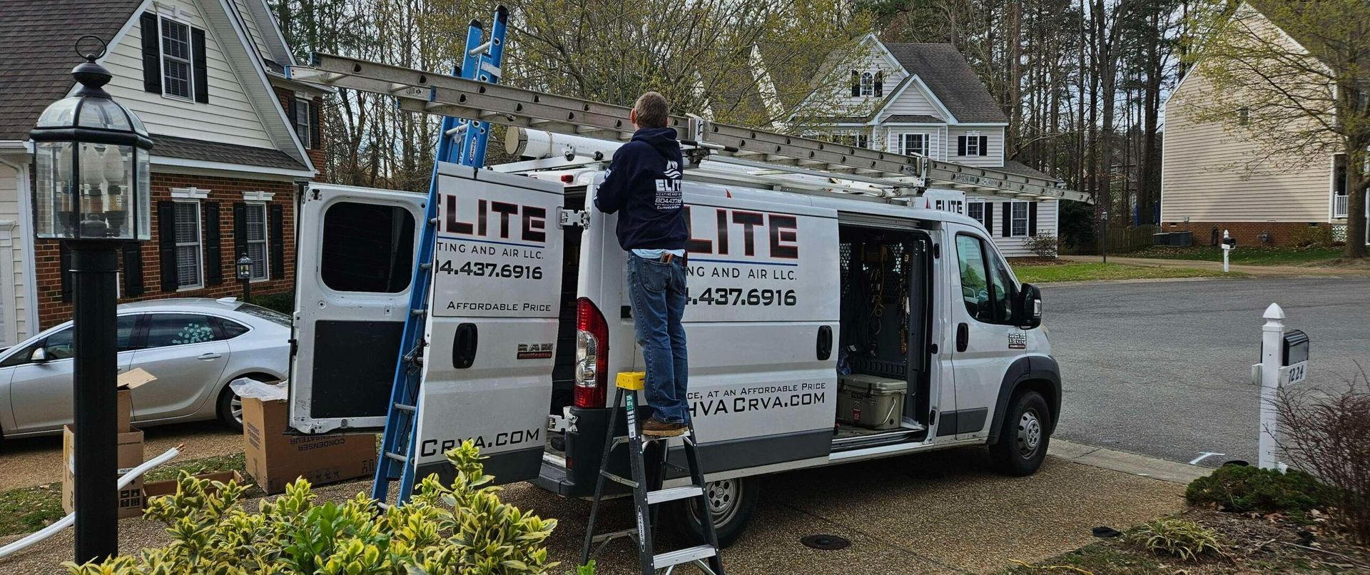 Two white moving trucks parked in a suburban driveway with workers unloading items
