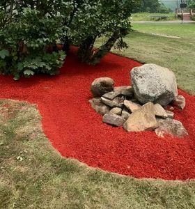 A garden filled with red mulch and rocks.
