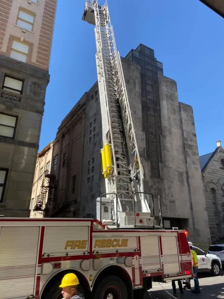 Fire truck with extended ladder reaching a tall building.