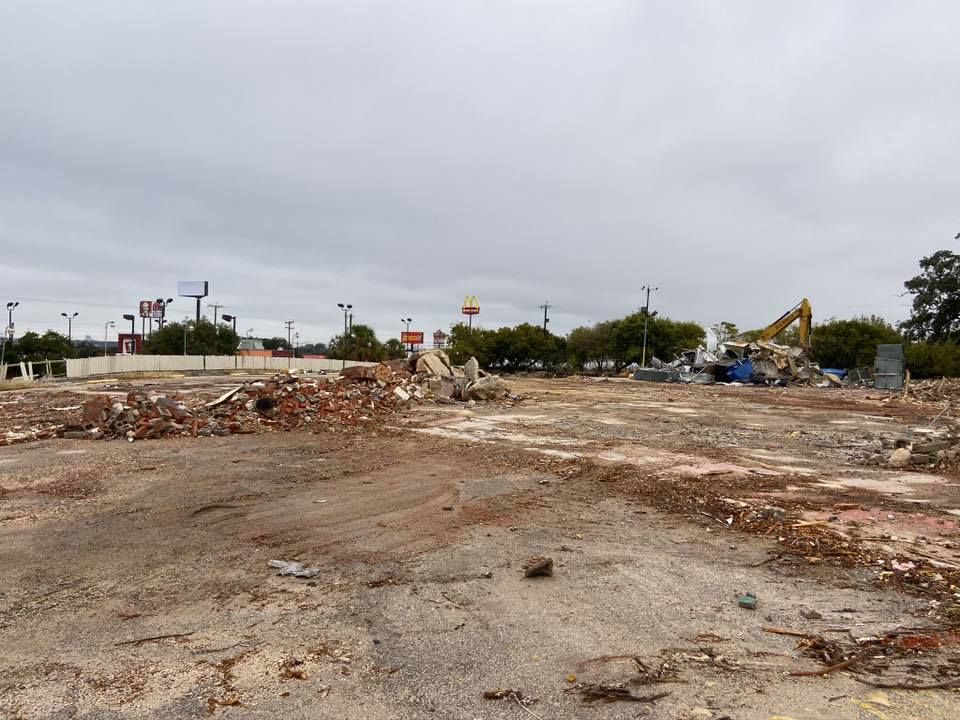 Demolished building site with scattered rubble under overcast sky.