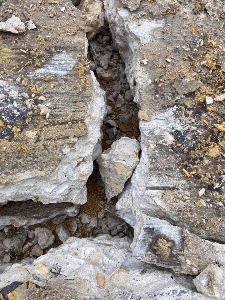 Close-up view of cracked concrete with dirt and small rocks in the crevice.