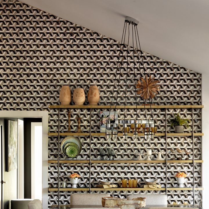 Geometric wallpapered wall with shelves holding decor; pendant light hangs down.