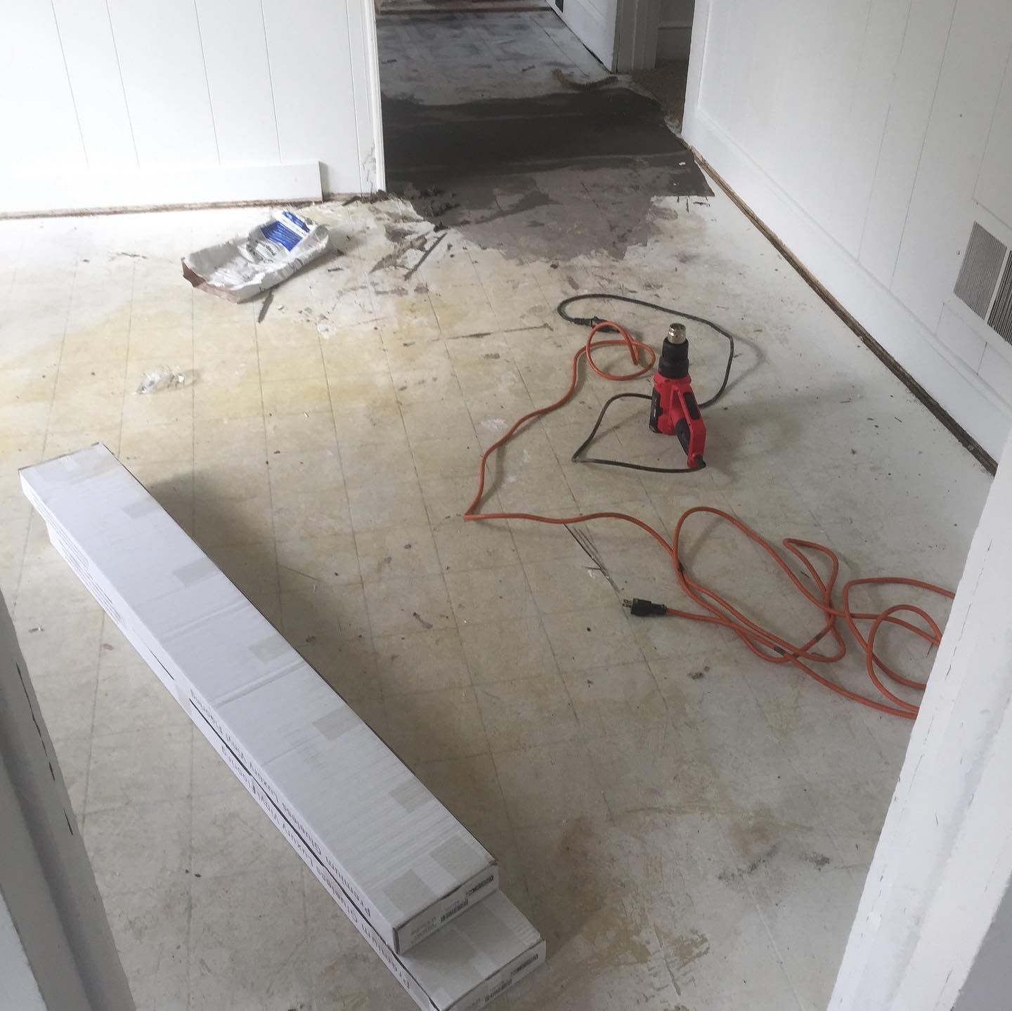 Room with exposed concrete floor, flooring boxes, and a heat gun.
