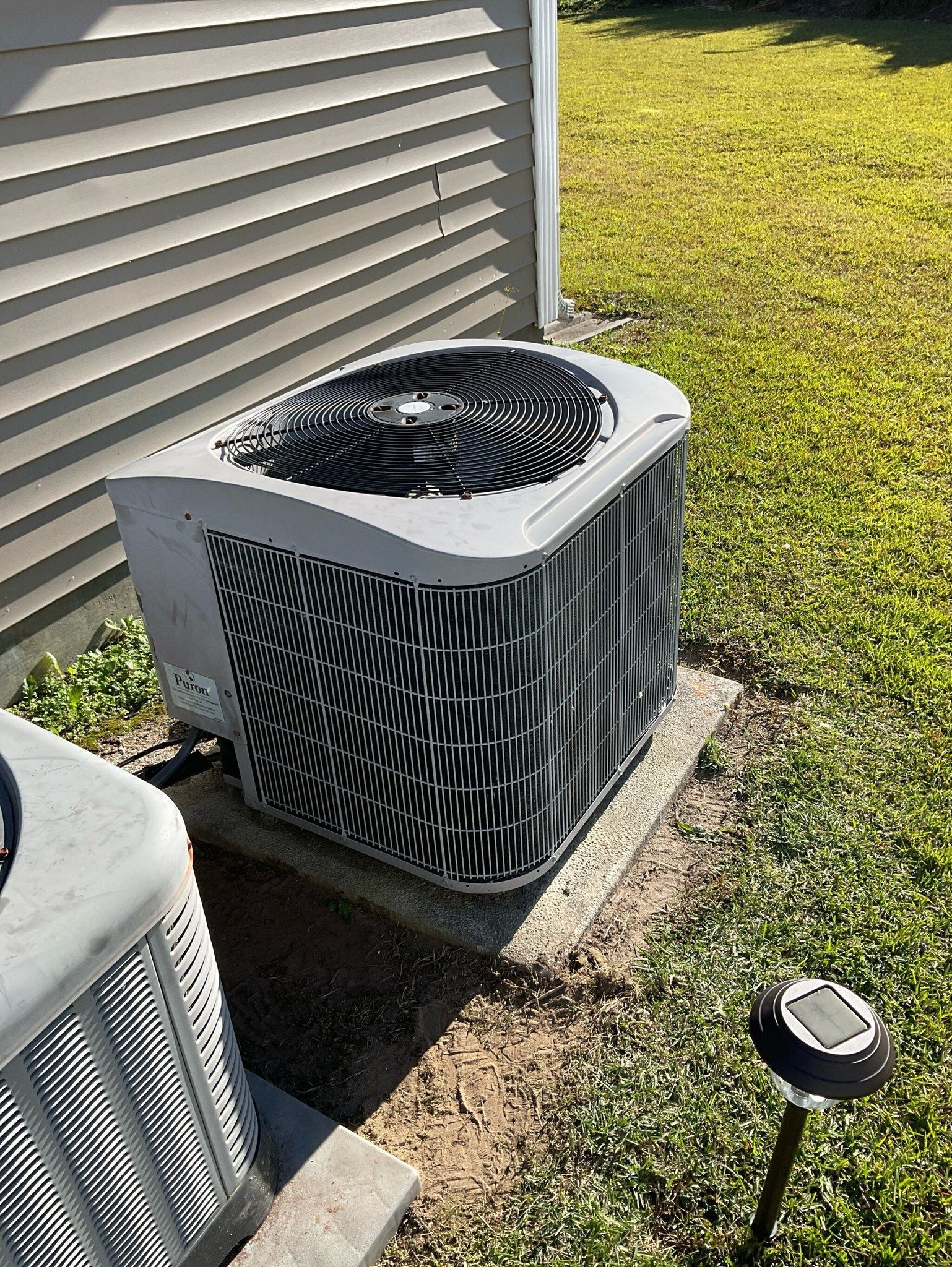 A large air conditioner is sitting on the side of a house