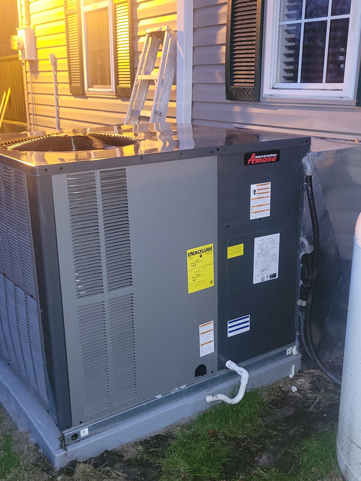 A large air conditioner is sitting on the side of a house