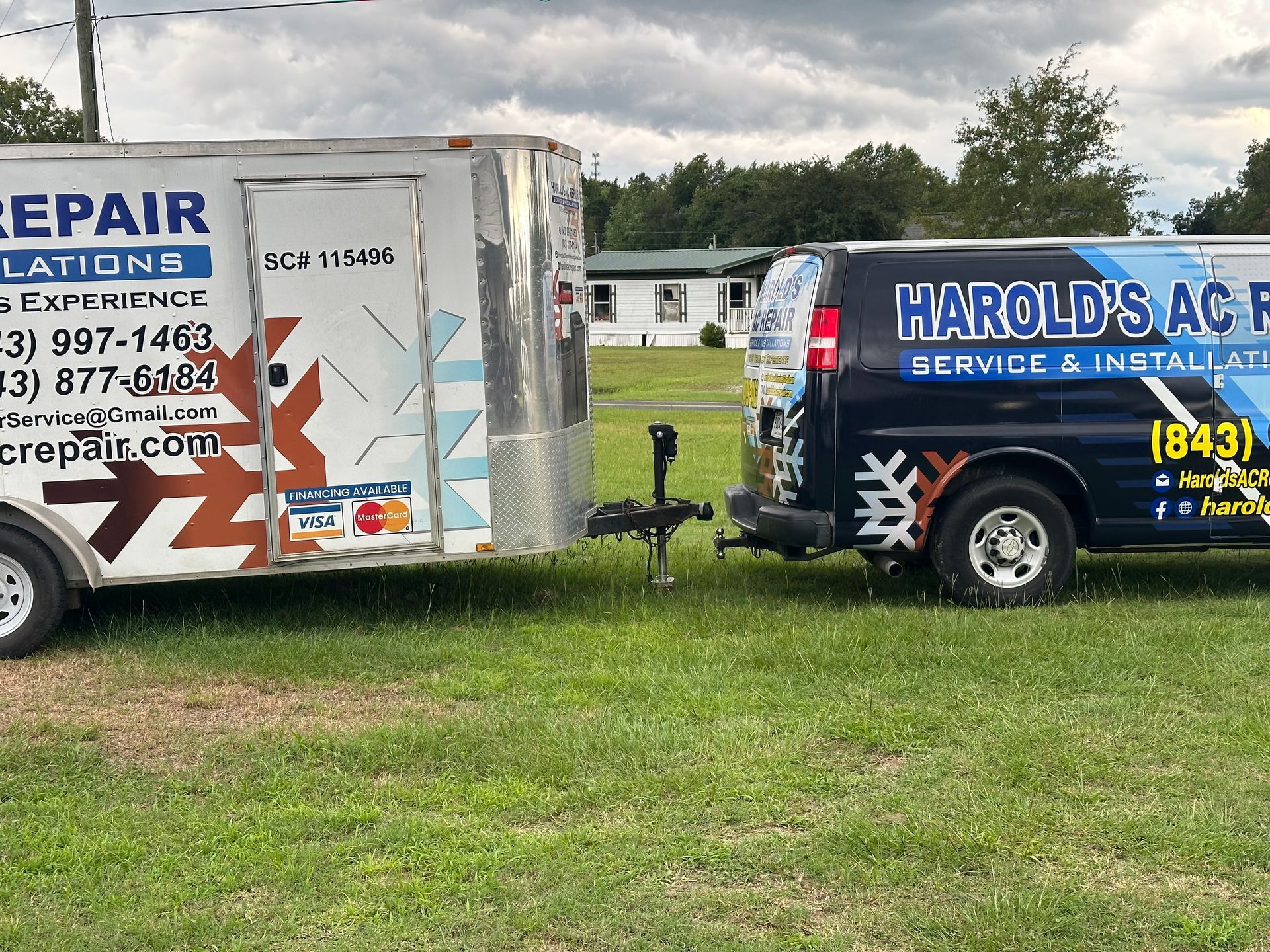 Two harold 's ac repair vans are parked next to each other in a grassy field.