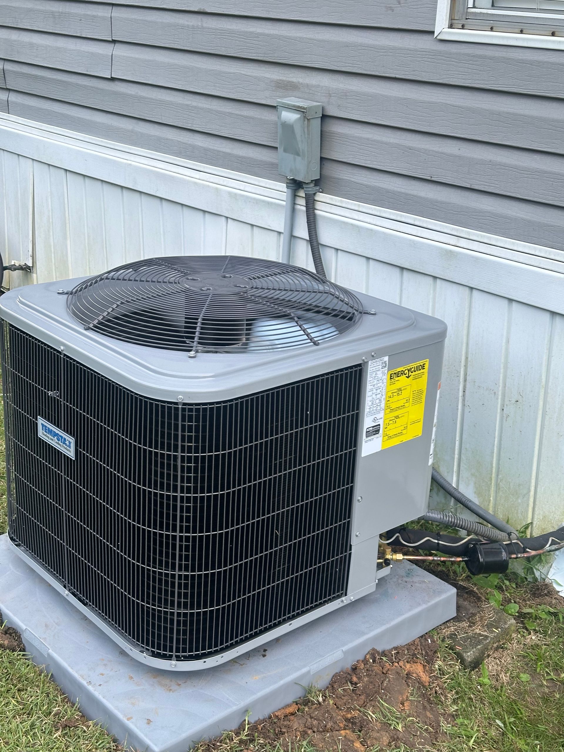 An air conditioner is sitting on the side of a house.