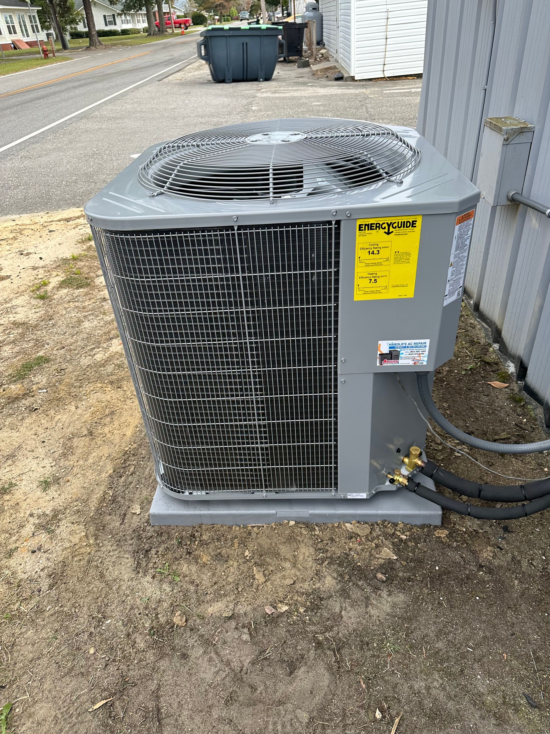 A large air conditioner is sitting on the ground next to a building.