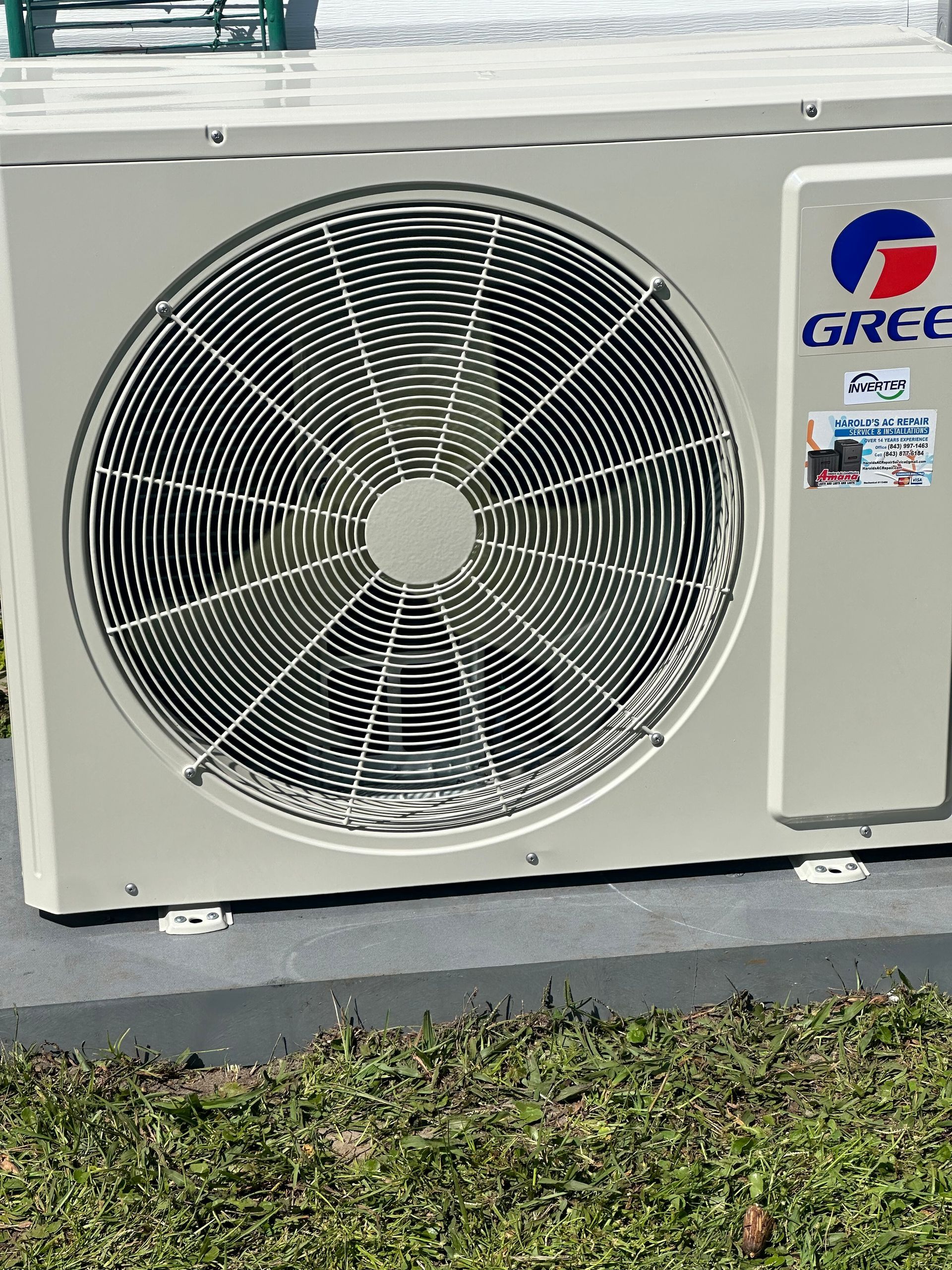 A gree air conditioner is sitting on top of a grass covered field.