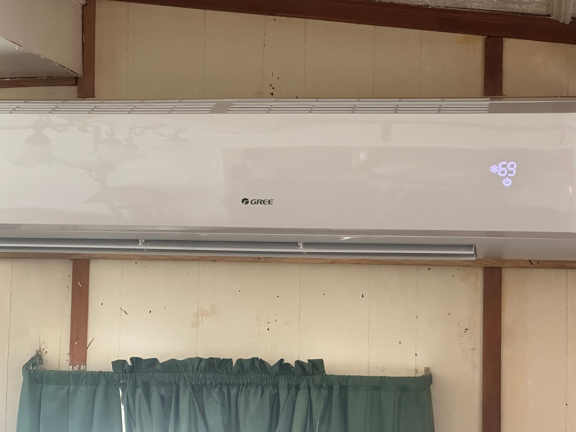 A white air conditioner is hanging from the ceiling in a room.