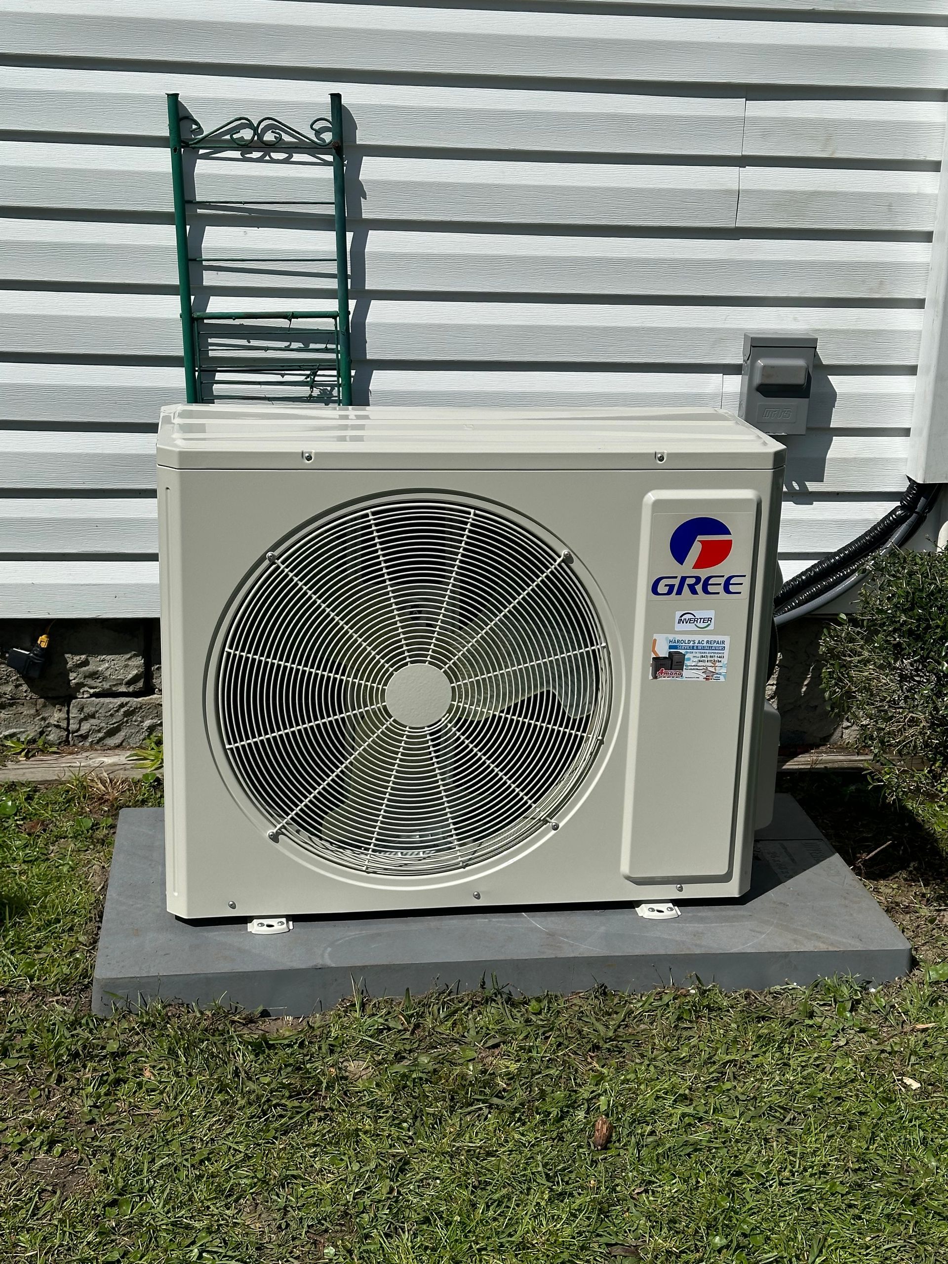 A white air conditioner is sitting outside of a house.