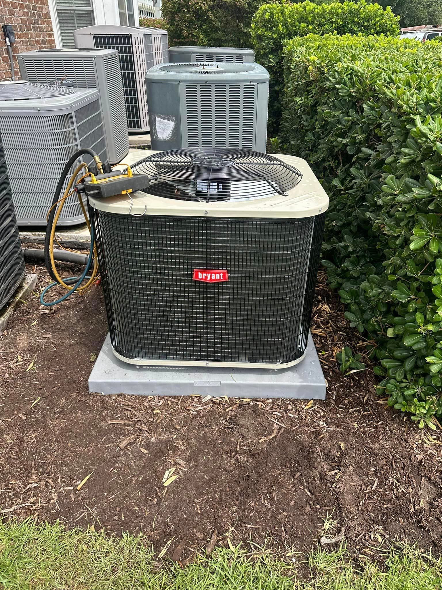 A large air conditioner is sitting on top of a concrete base in a yard