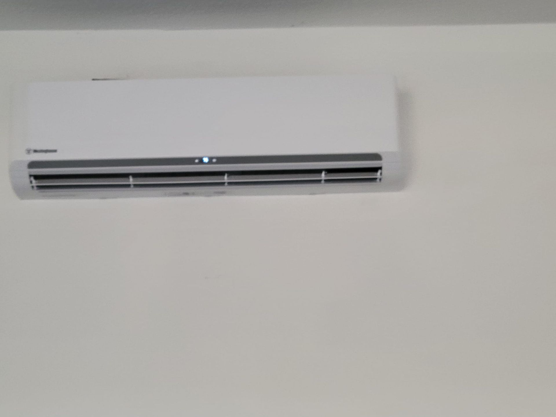A white air conditioner is hanging on a white wall
