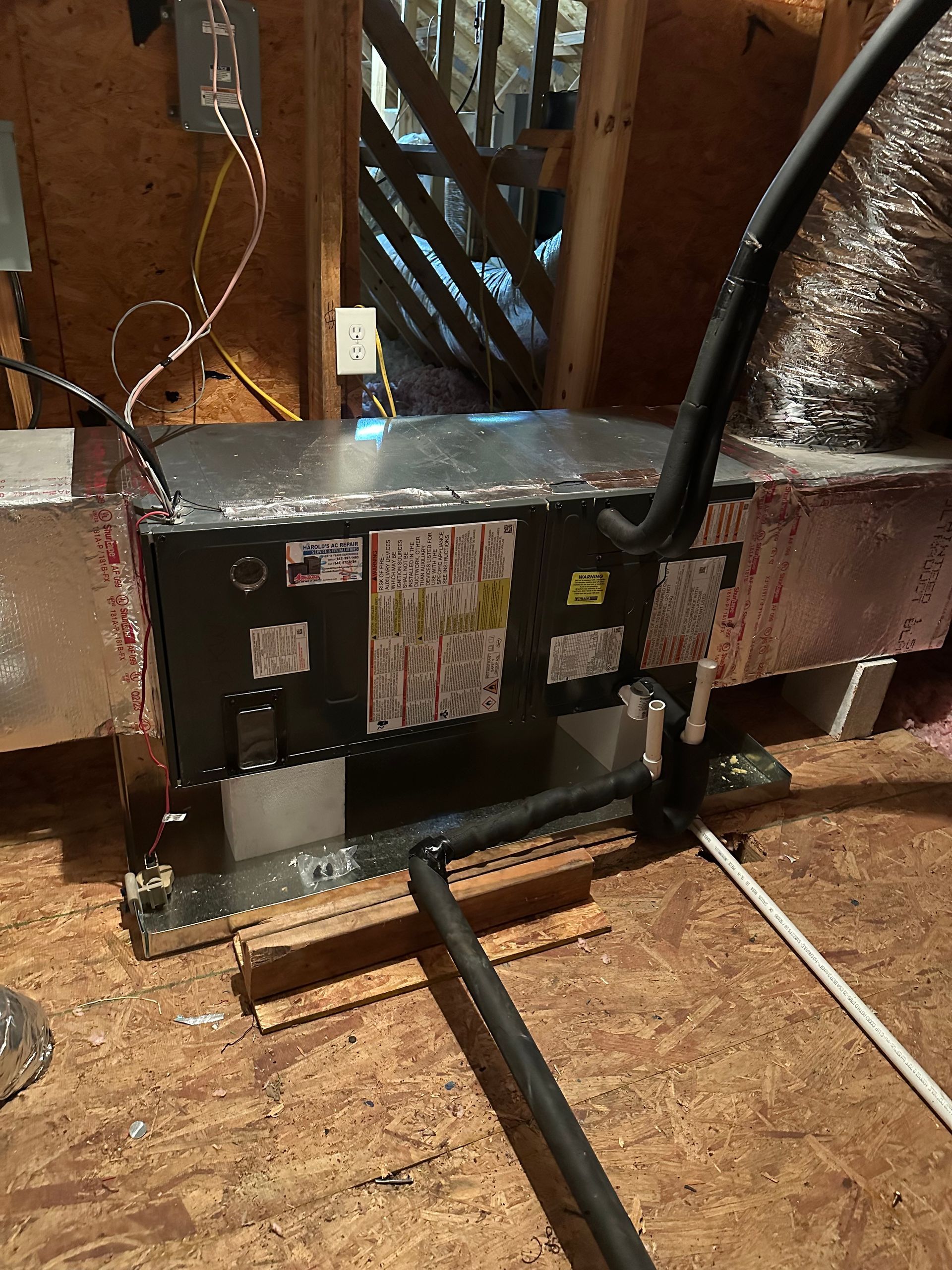 An air conditioner is sitting in the attic of a house.