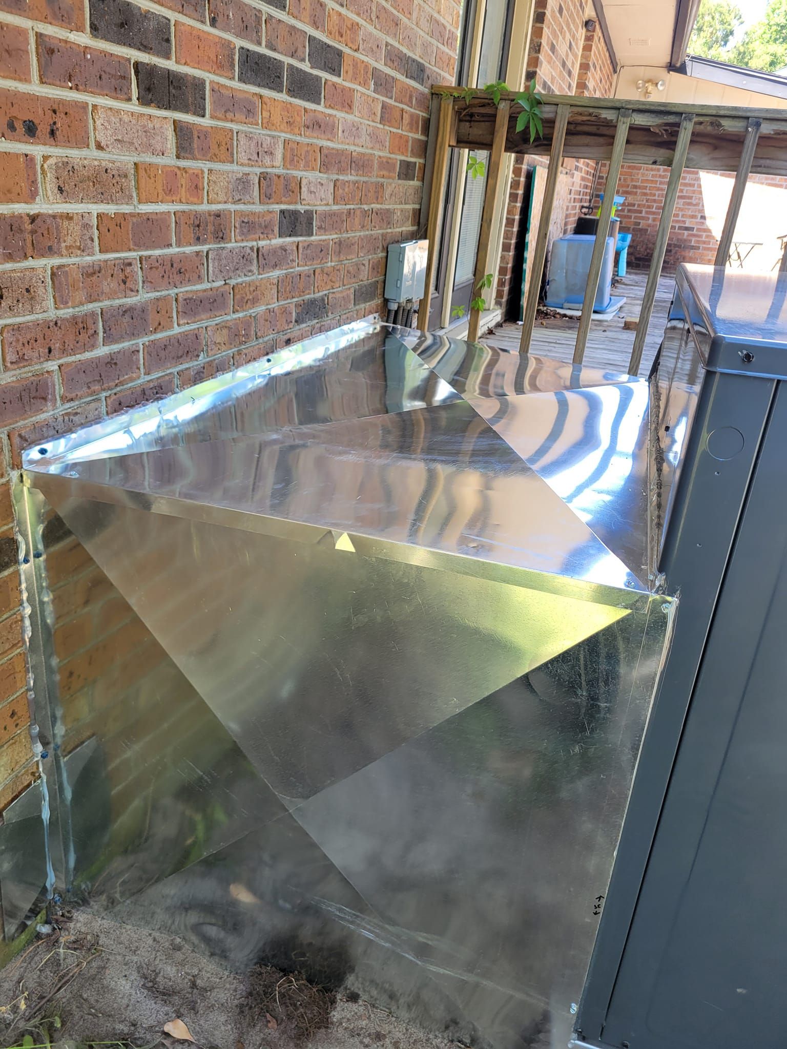 A metal box is sitting on the side of a brick building