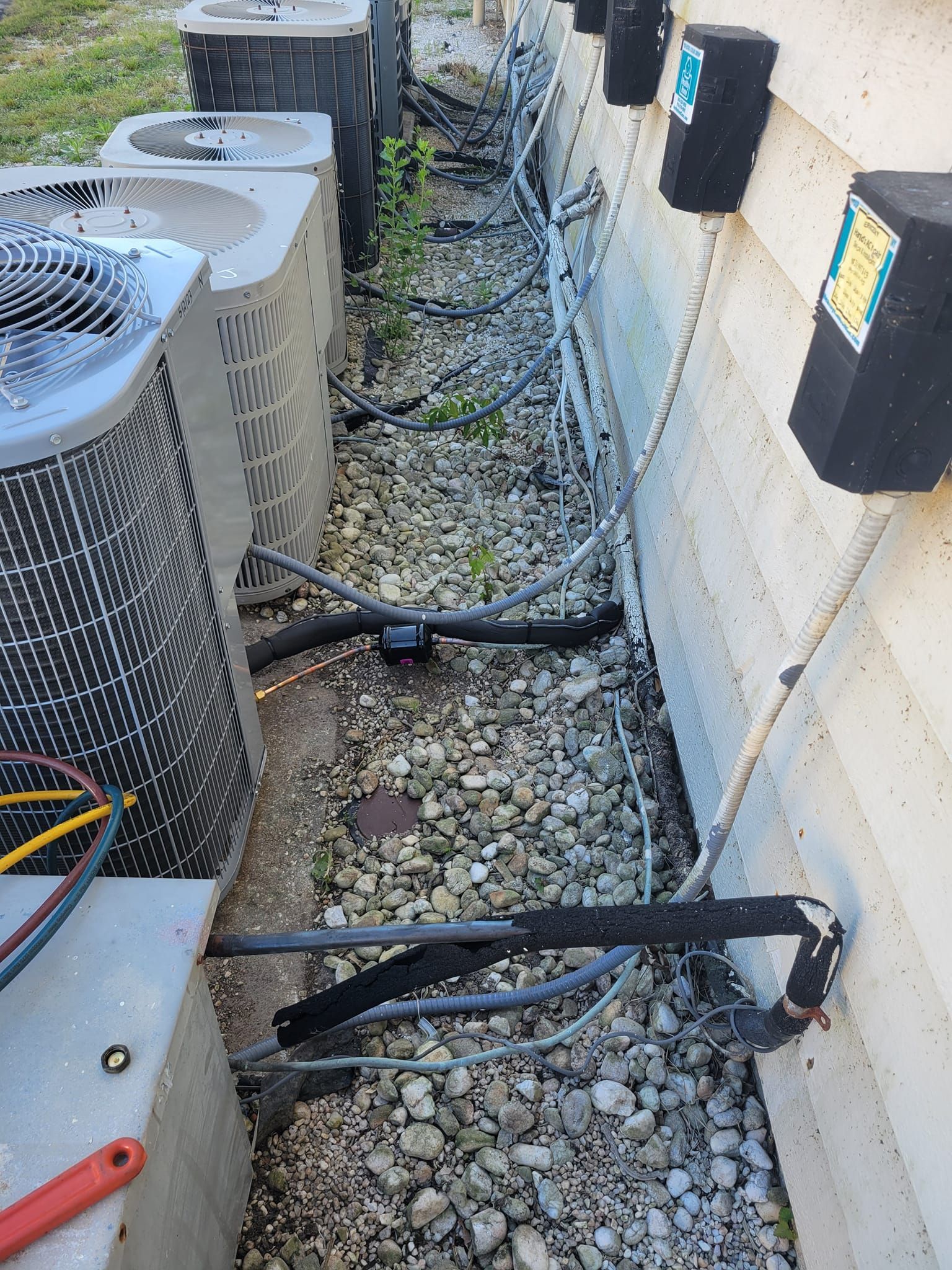 A row of air conditioners are sitting next to each other on the side of a building