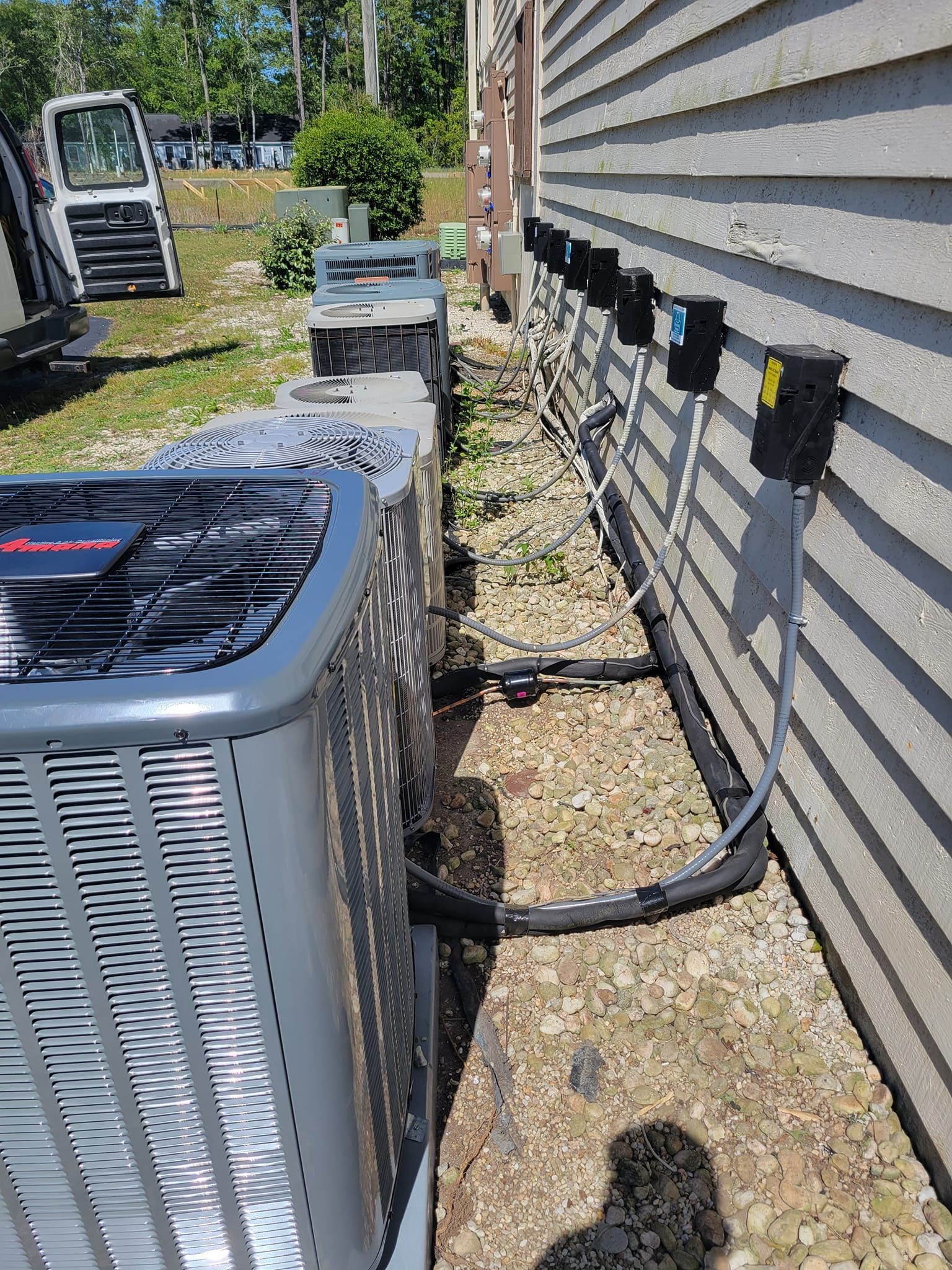 A row of air conditioners are sitting on the side of a house