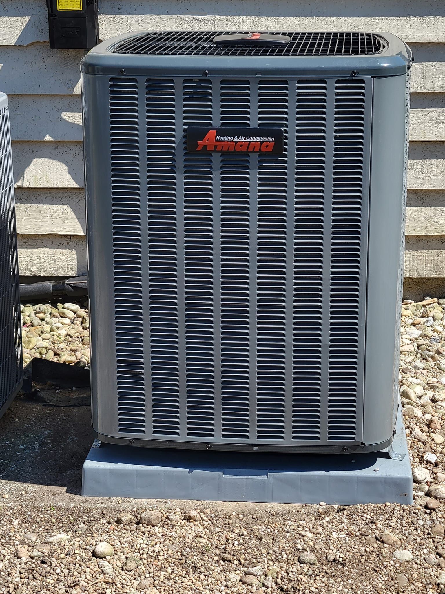 An air conditioner is sitting on top of a pile of gravel