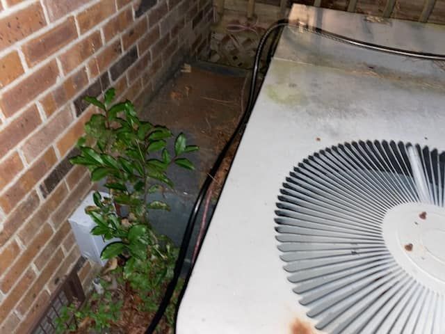 A dirty air conditioner is sitting next to a brick wall