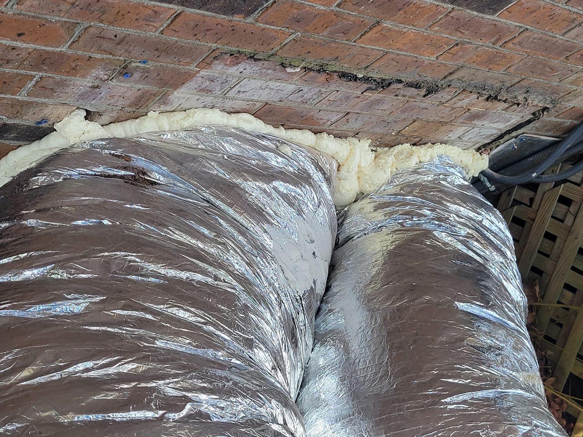 A duct is sitting on top of a brick wall