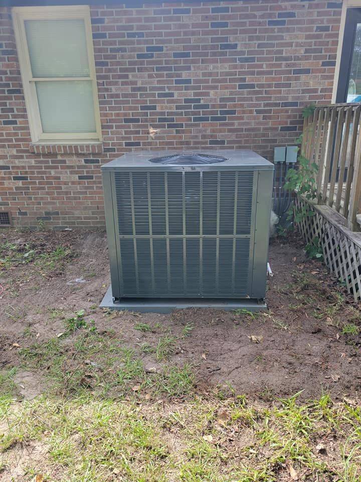 A large air conditioner is sitting in the backyard of a brick house