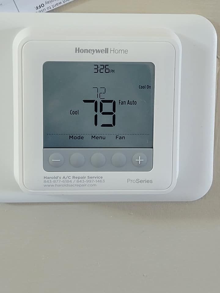 A white honeywell home thermostat is sitting on a wall