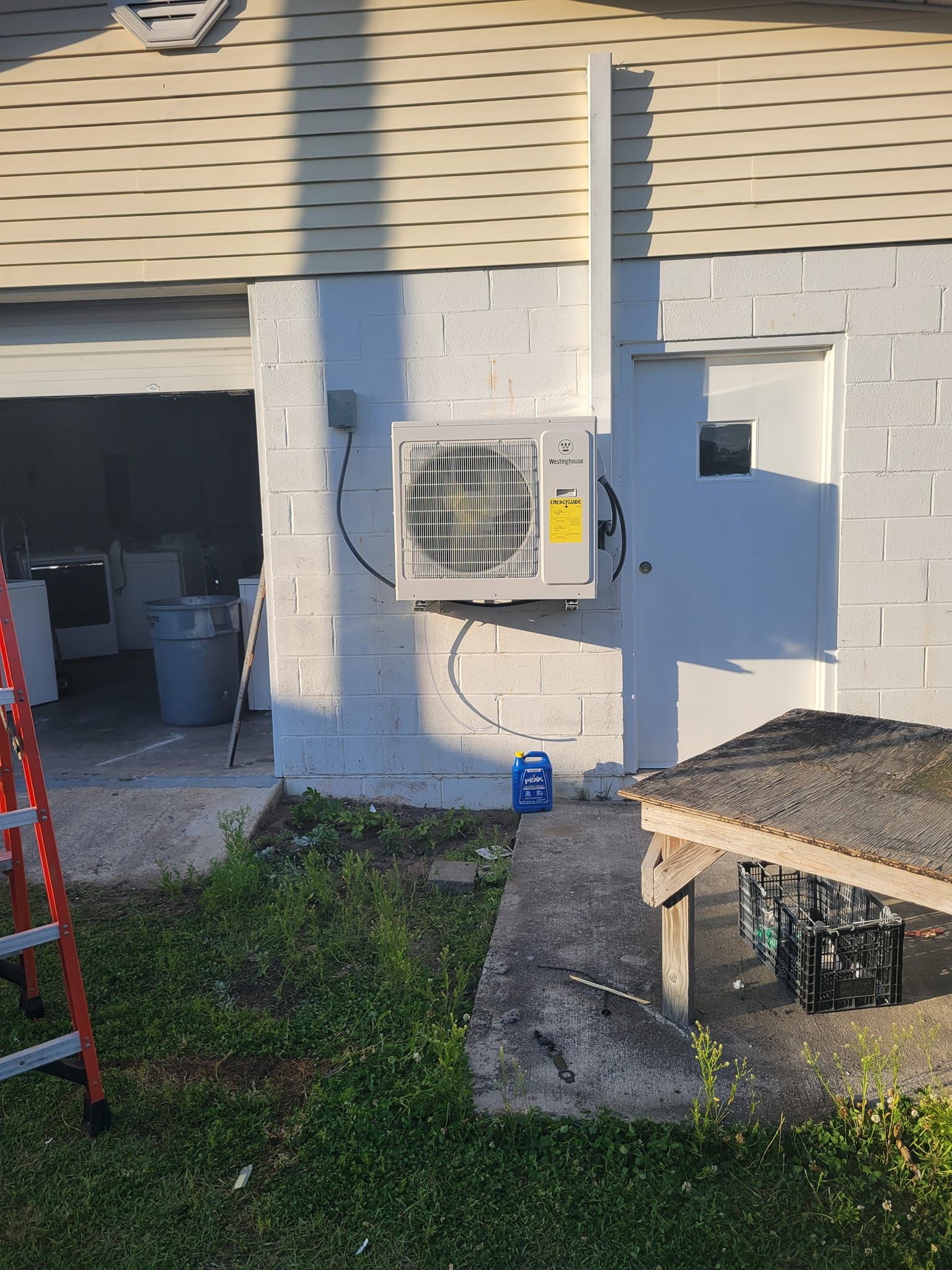 An air conditioner is hanging on the side of a white brick building