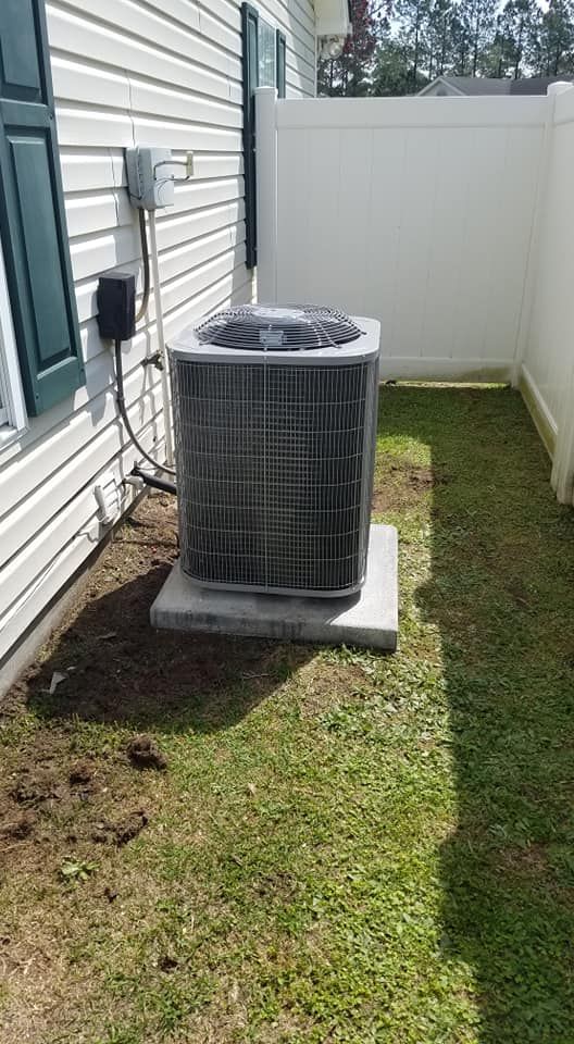 A large air conditioner is sitting in the backyard of a house
