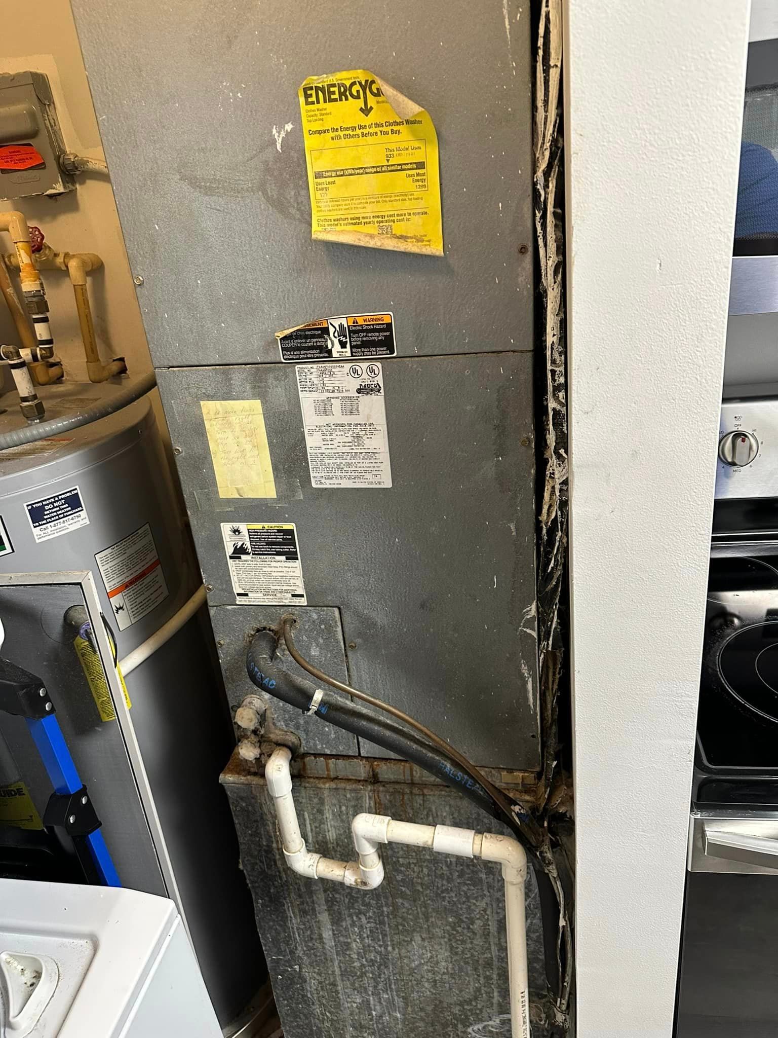 A water heater is sitting next to a wall with a sticker 