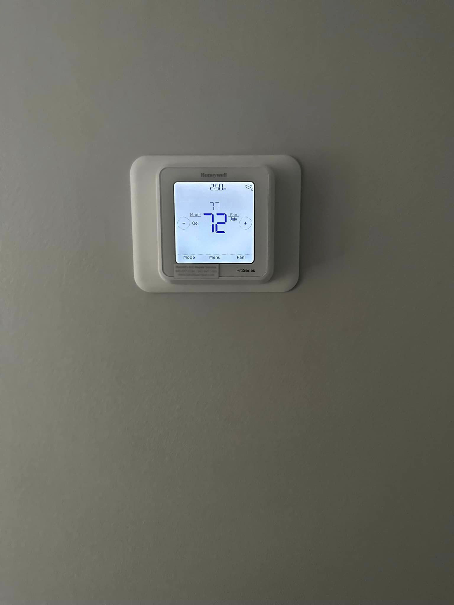 A thermostat is hanging on a wall and the temperature is 72 degrees fahrenheit