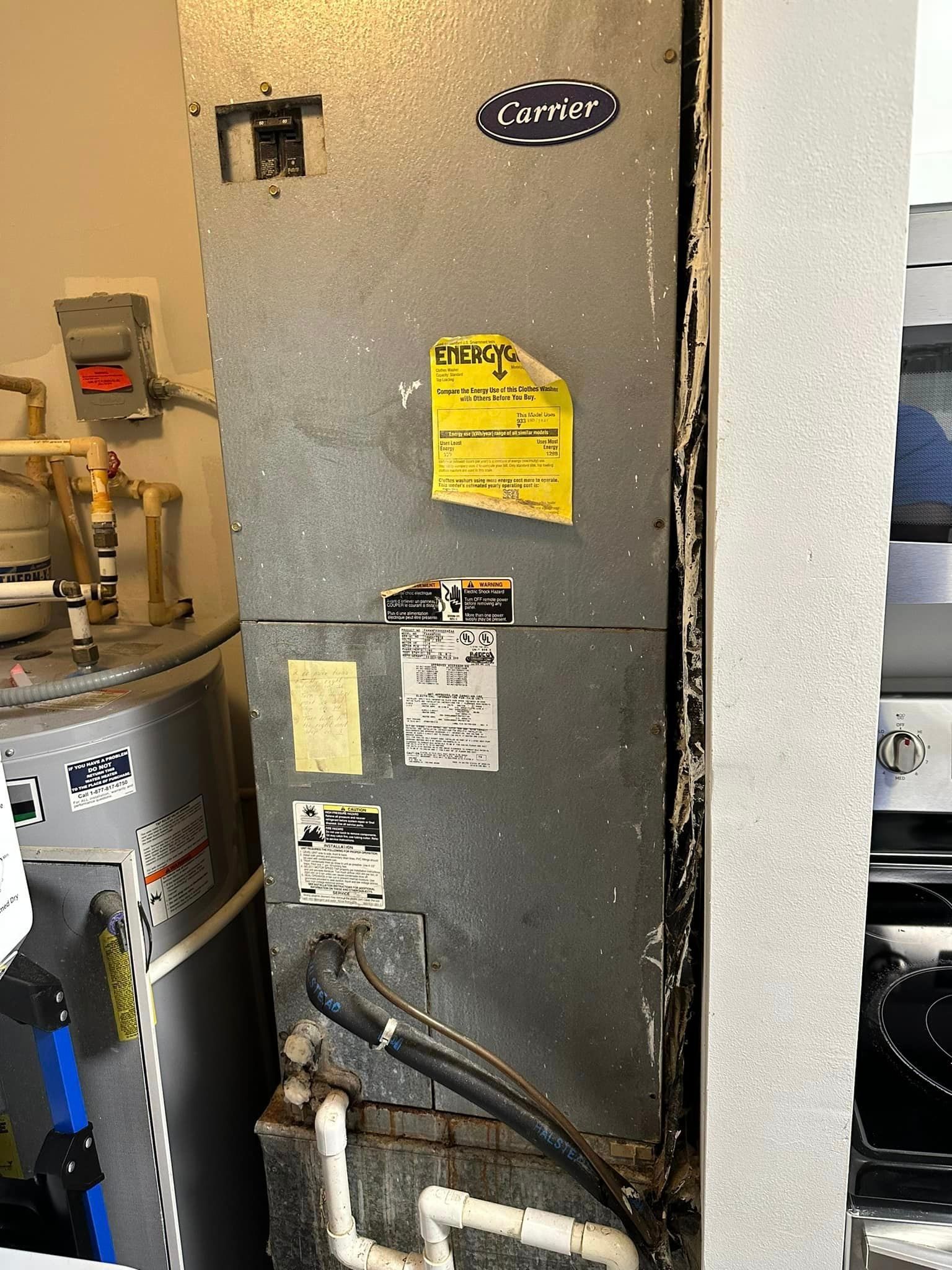 A dirty air conditioner is sitting in a room next to a stove