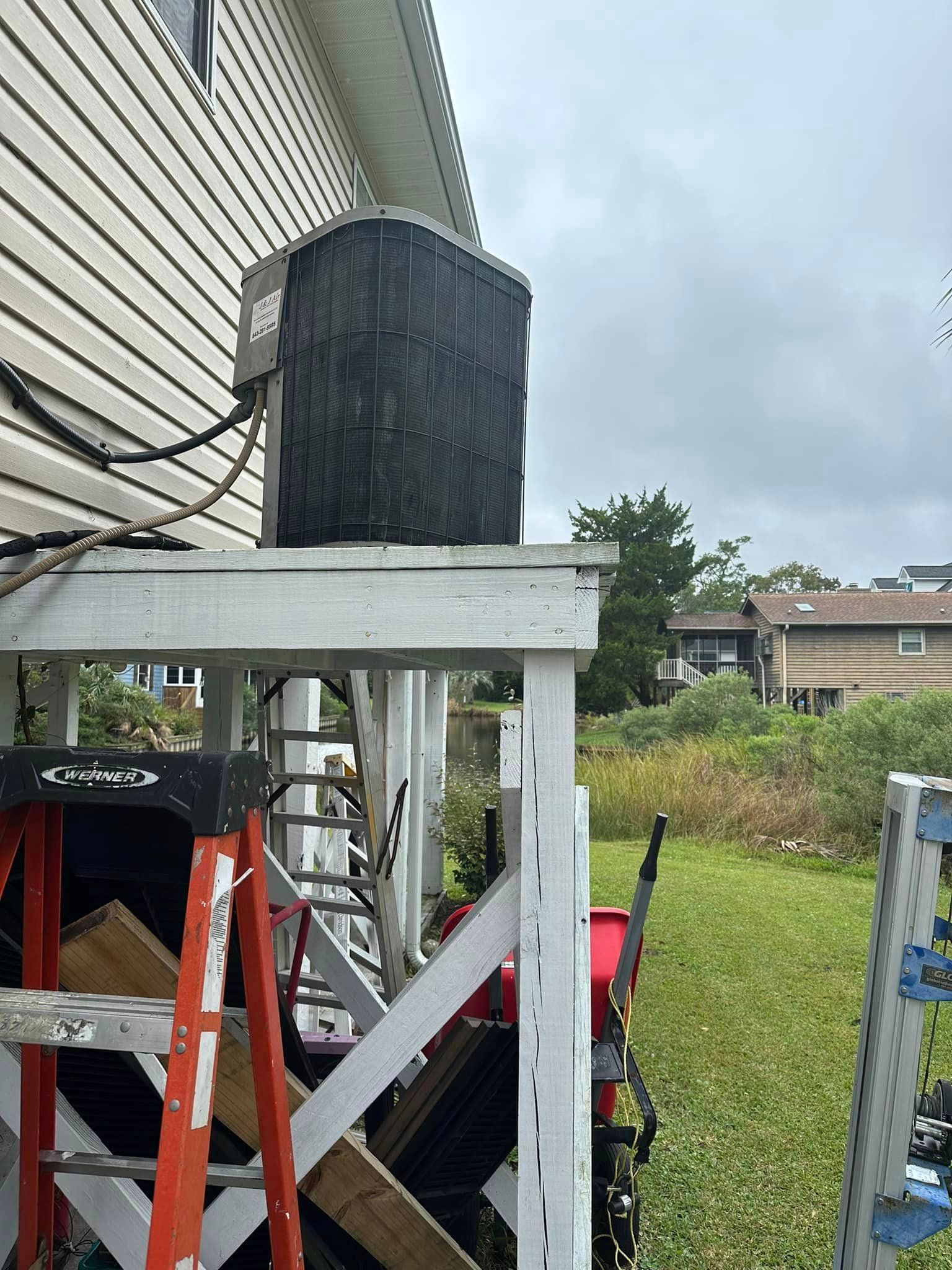A ladder is sitting on top of a wooden platform next to a house