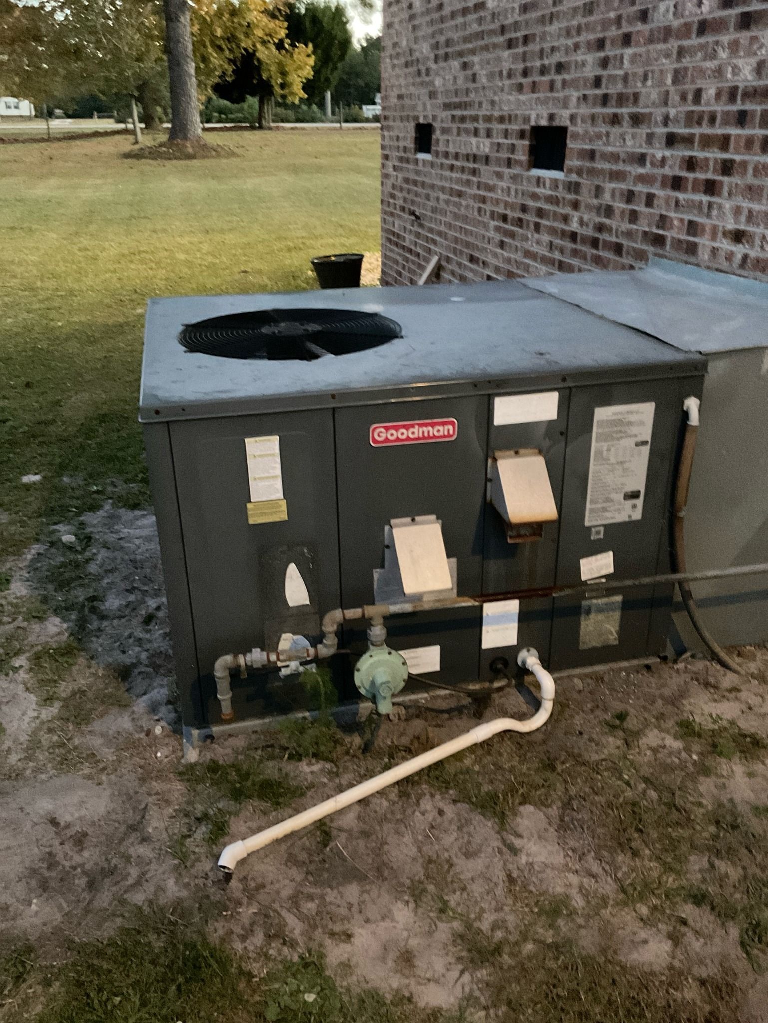 An air conditioner is sitting in the grass next to a brick building