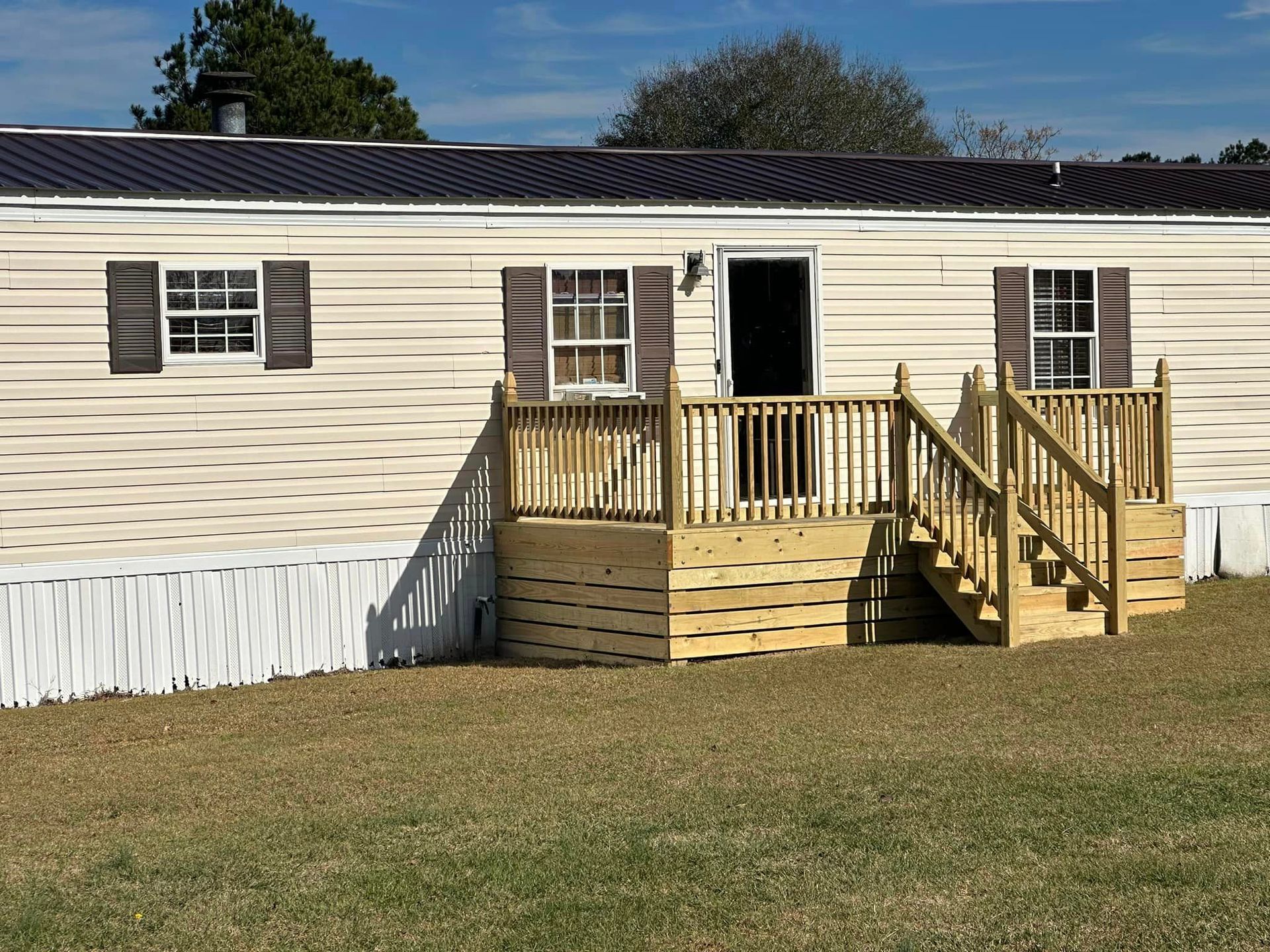 A mobile home with a wooden deck and stairs