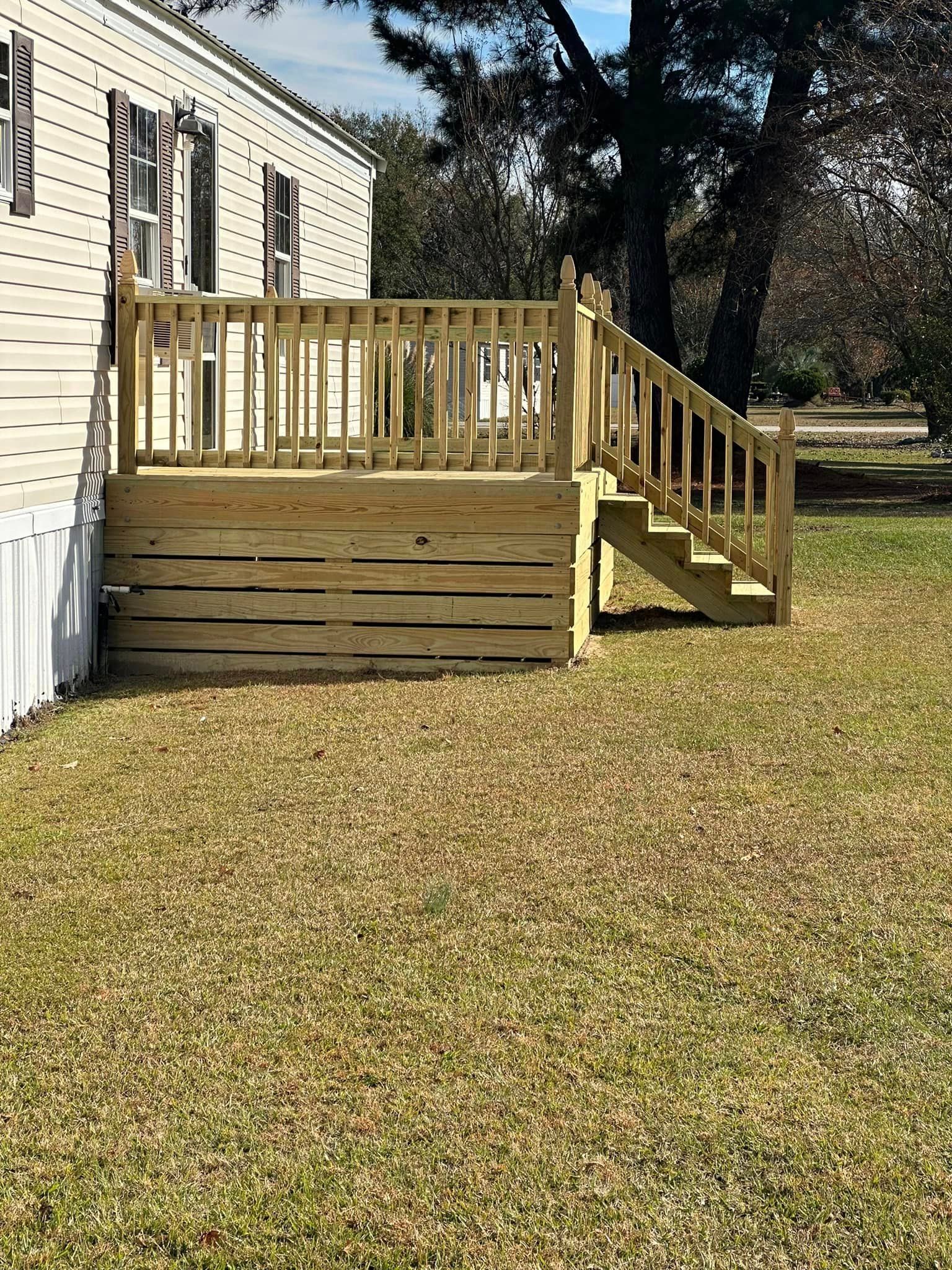 A mobile home with a wooden deck and stairs in front of it