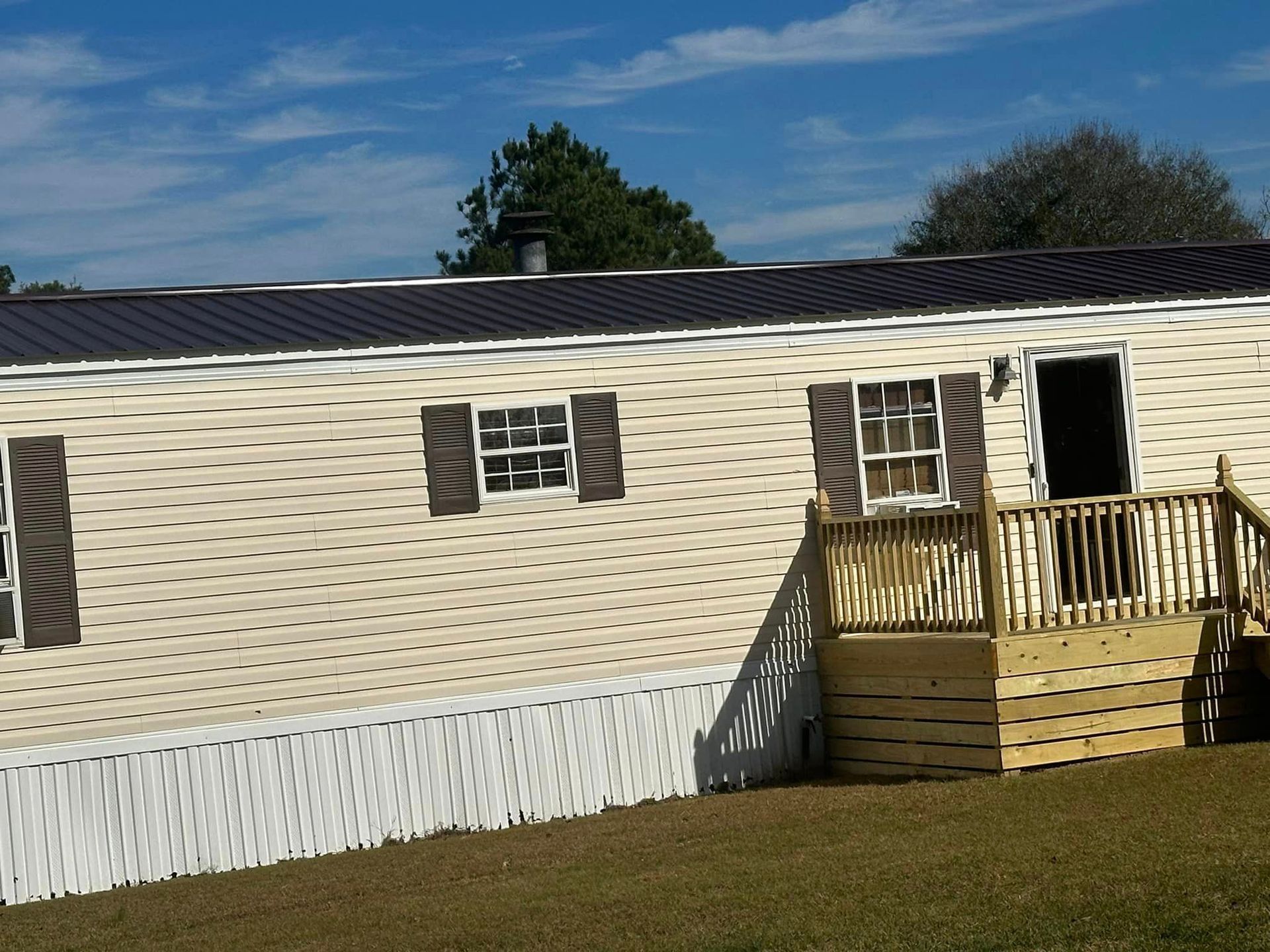 A mobile home with a wooden deck and stairs