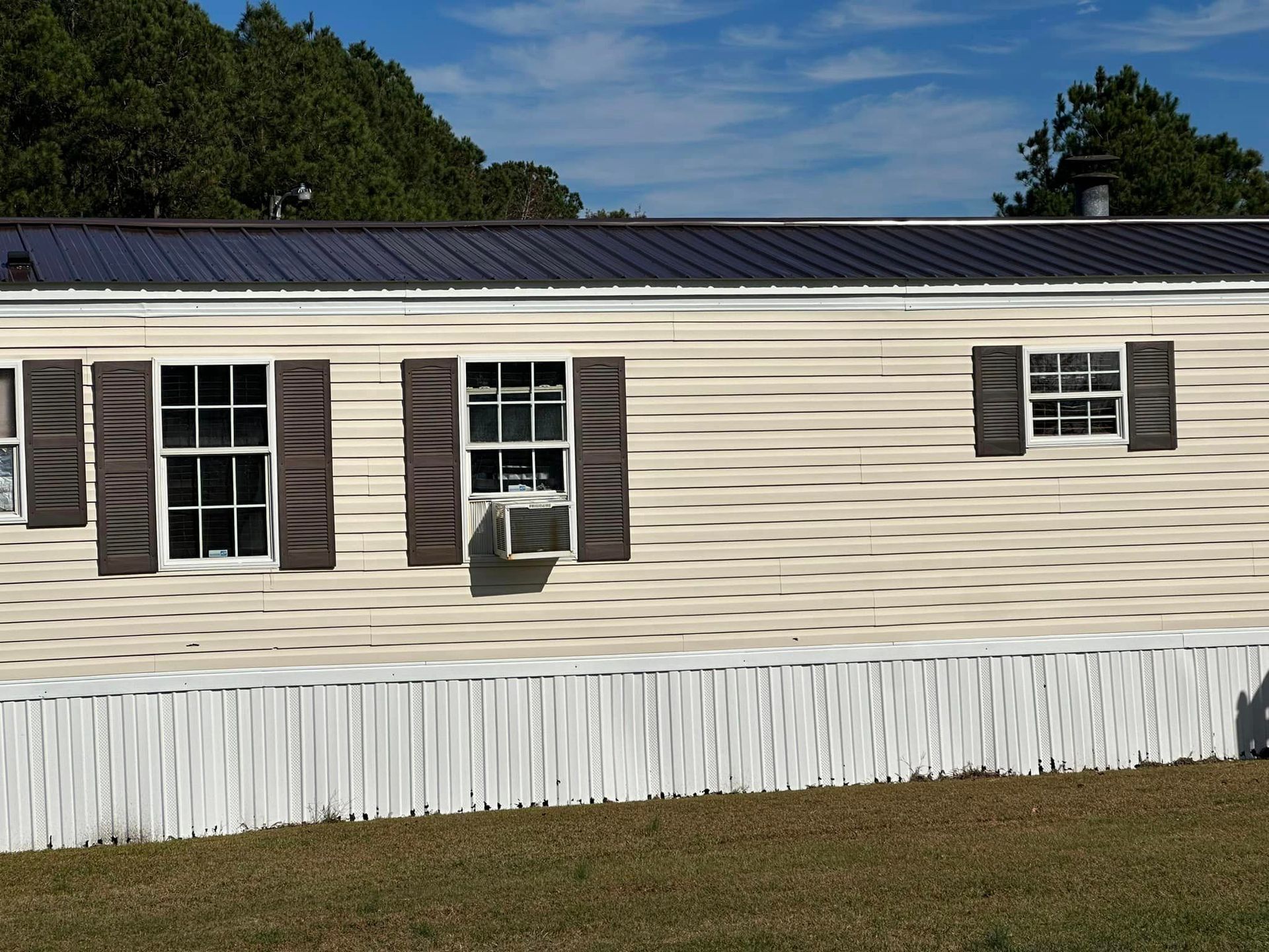 A mobile home with shutters on the windows and a black roof
