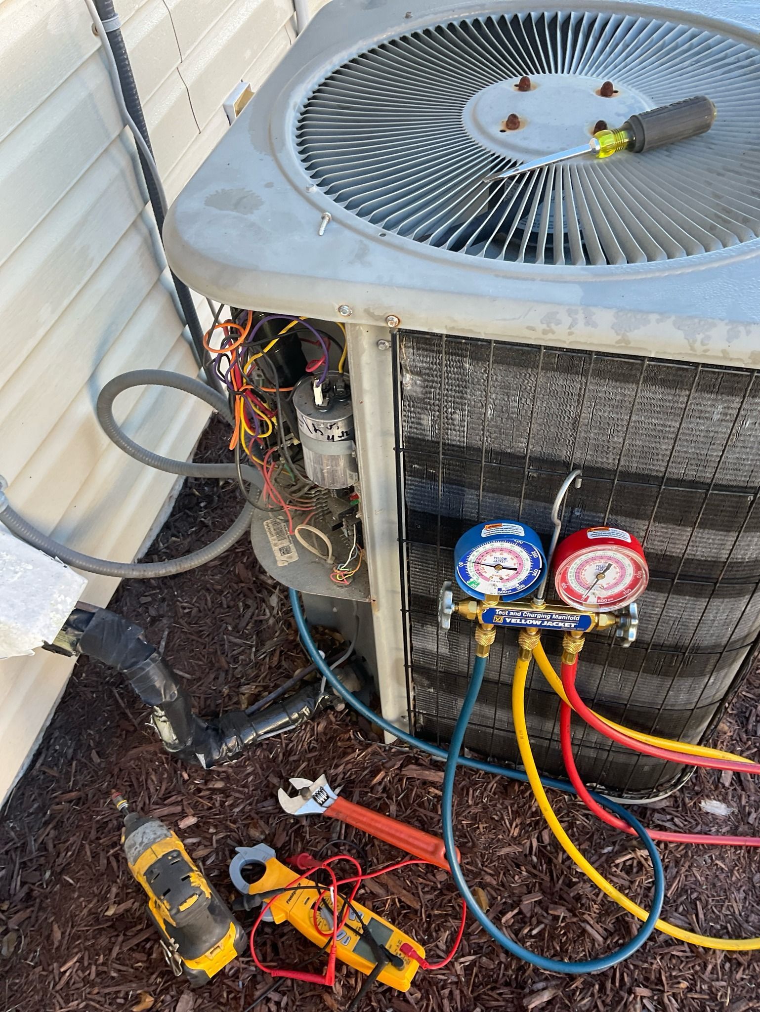 An air conditioner is being repaired on the side of a house