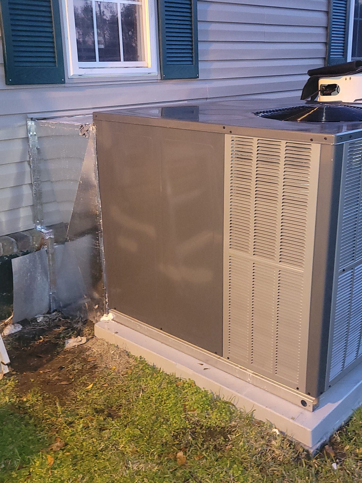 A gray box is sitting in the grass in front of a house