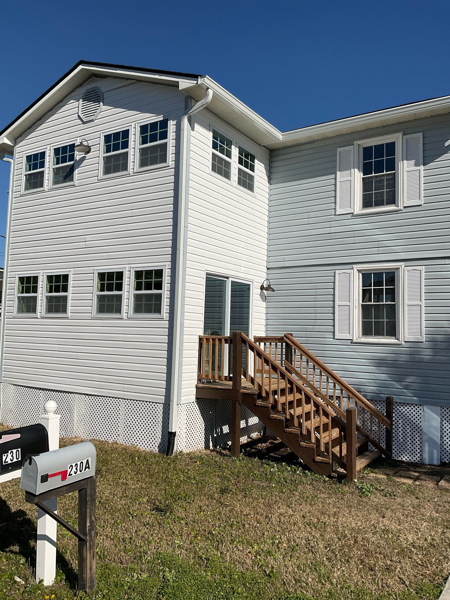 A white house with stairs and a mailbox in front of it