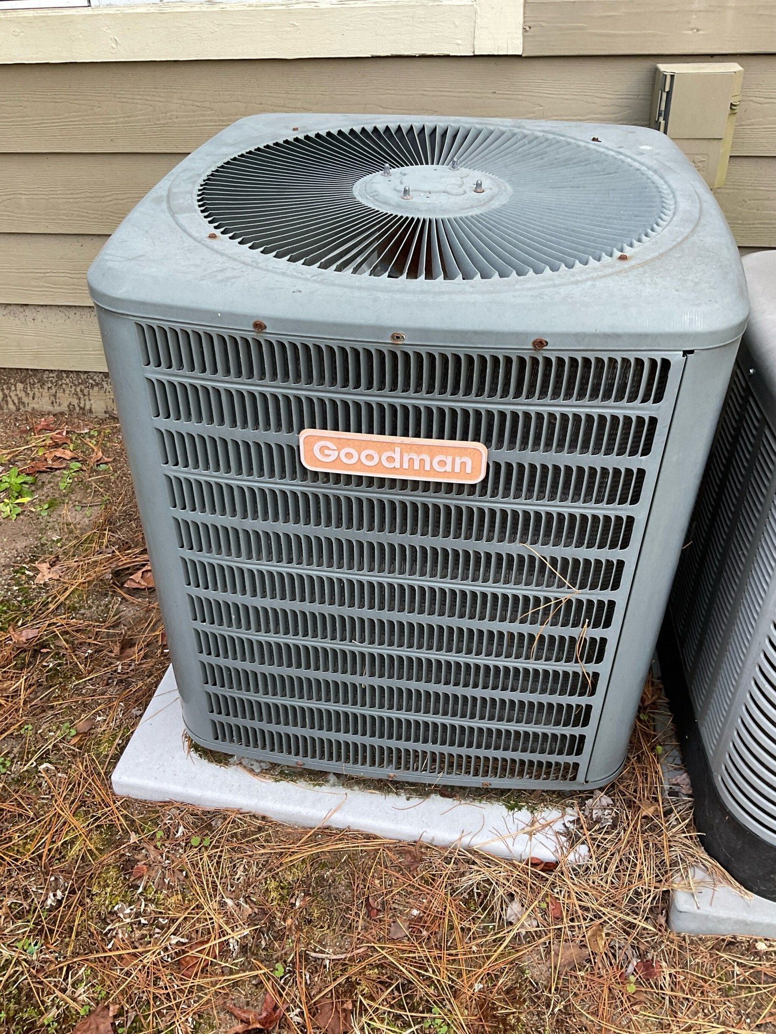 A gray air conditioner is sitting on top of a white concrete block