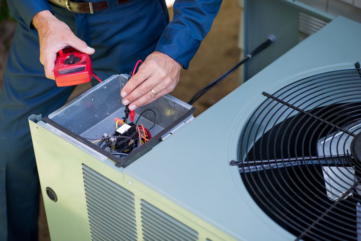 A man is working on an air conditioner with a multimeter