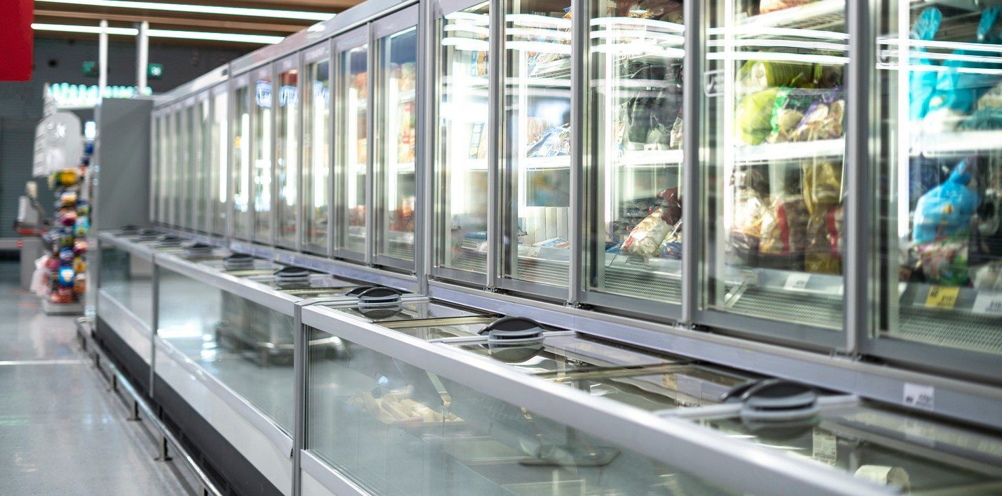 A row of refrigerators in a grocery store filled with food