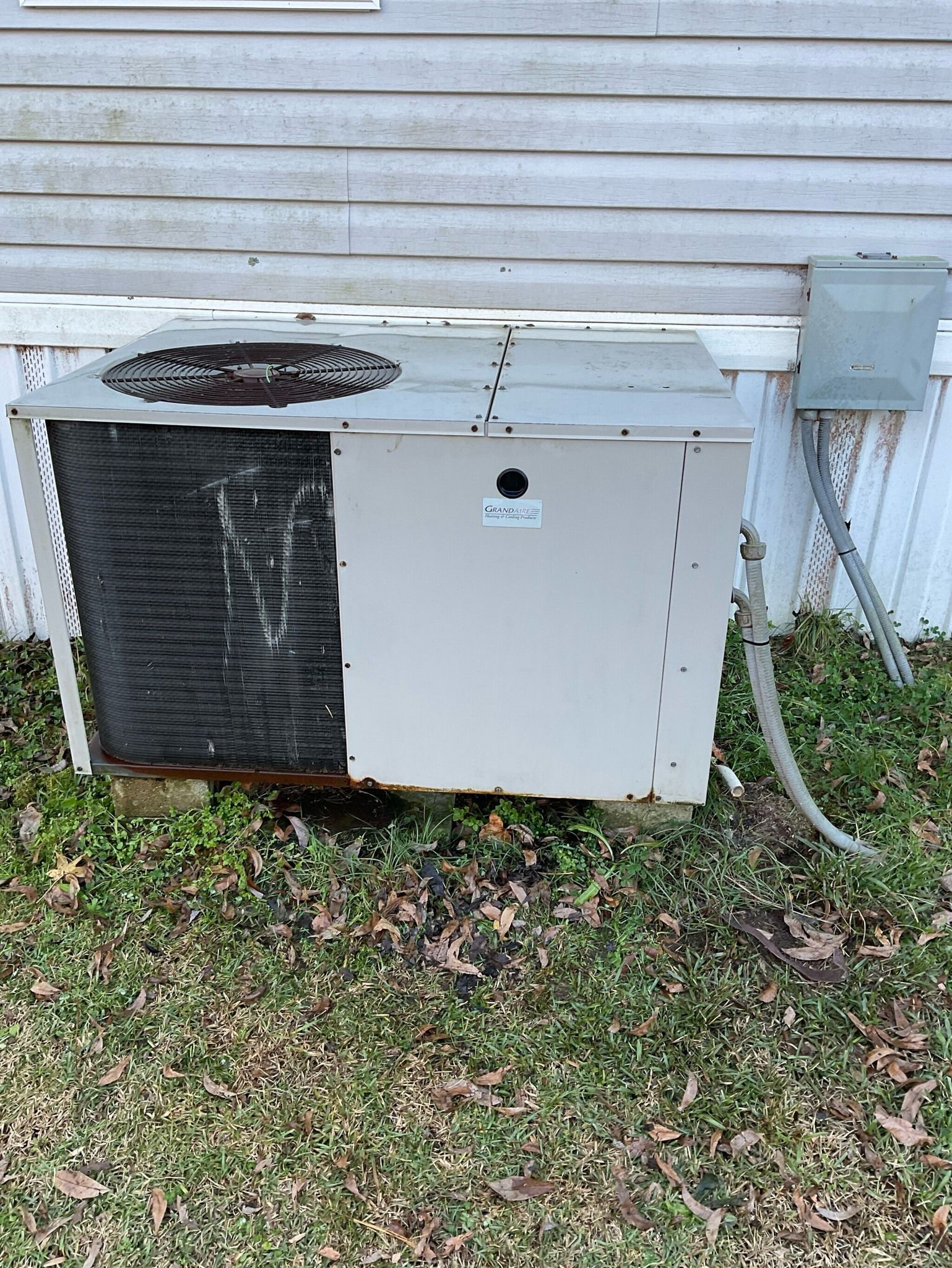 An old air conditioner is sitting on the side of a house