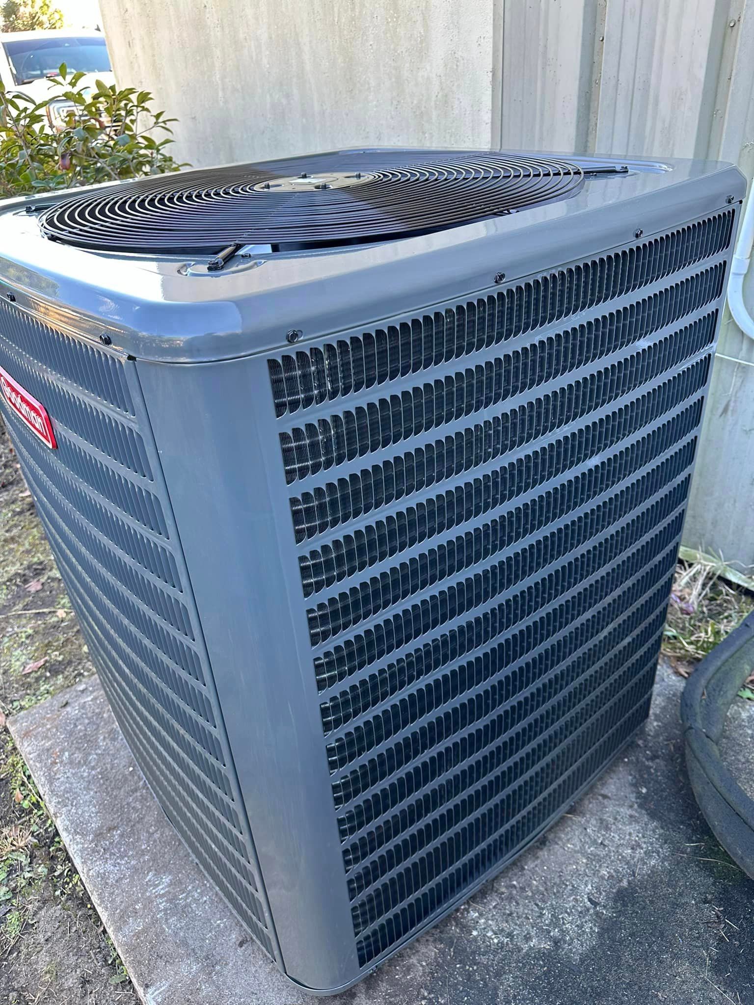 A large gray air conditioner is sitting on top of a concrete surface.