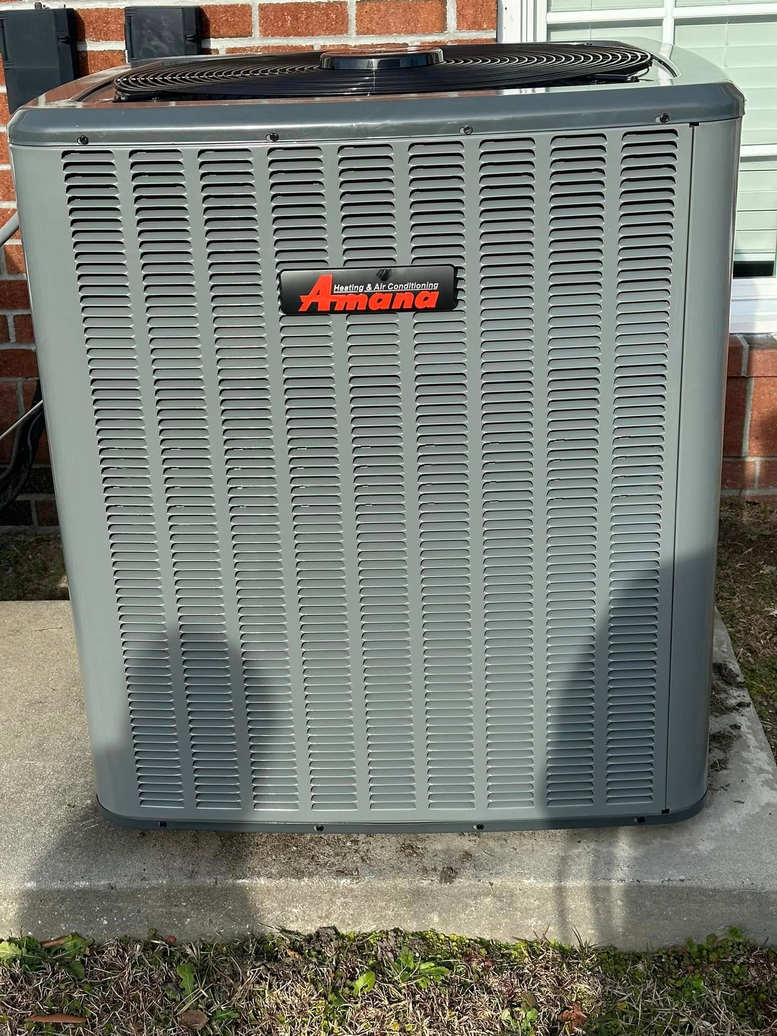 An air conditioner is sitting on the side of a brick building.